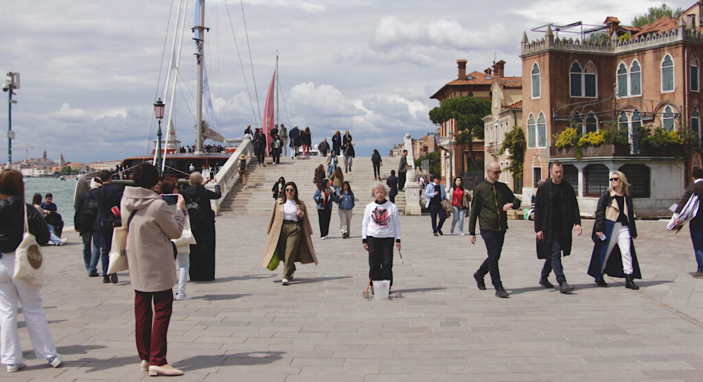 The artist stands still in the middle of a crowd in Venice, Italy.